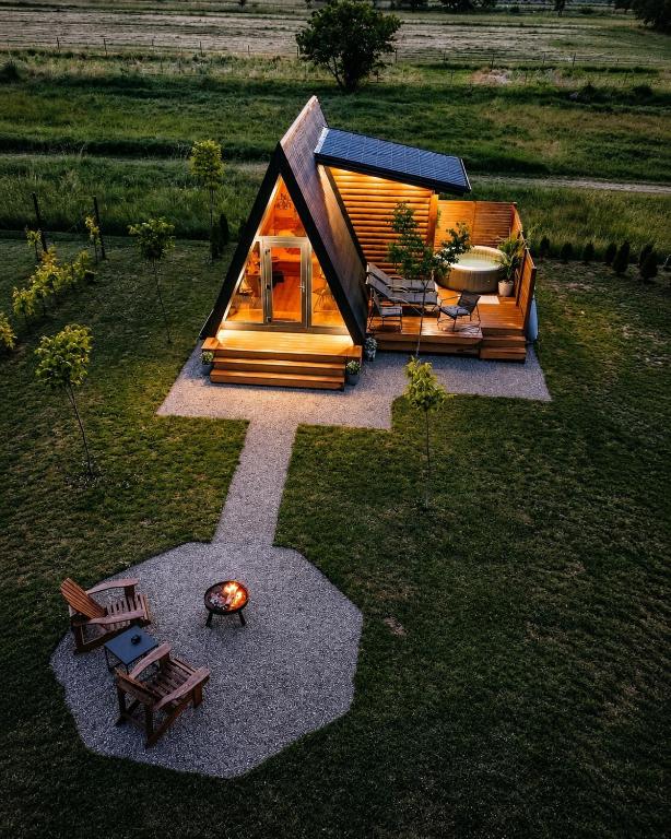 Aerial view of the illuminated A-frame chalet, hot tub terrace and fire pit at dusk