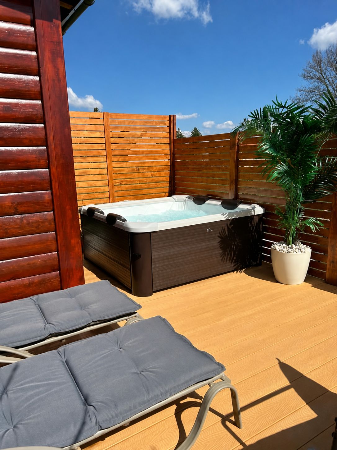 Private hot tub and two loungers on the chalet's timber terrace